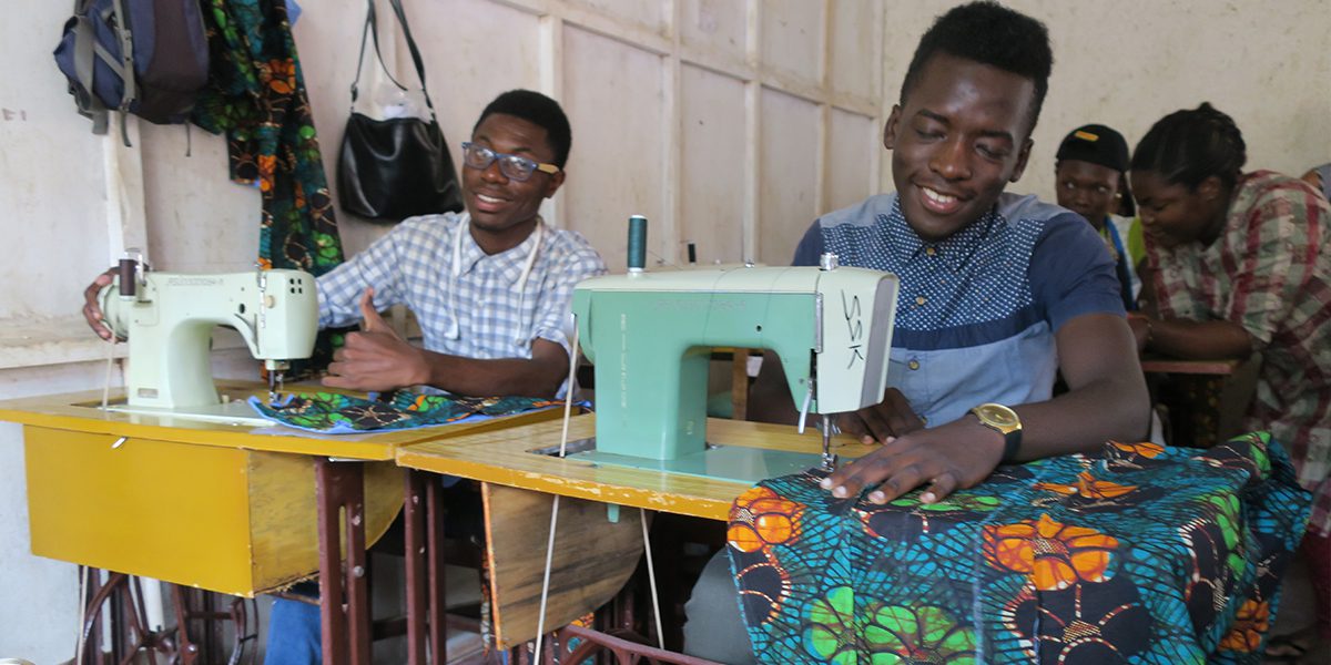 Two students work diligently in their tailoring class in JRS Kampala.